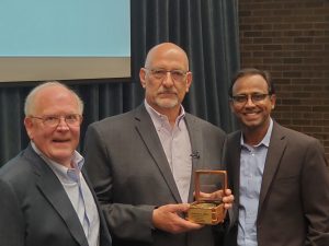 Greg Taucher holding the Hopp Faculty Fellow Award, next to Tony Hopp and Dean Prabu David