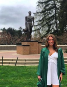 Young woman standing near the Spartan Statue on campus.