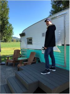 Man stands in front of camper, smiling.