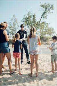 Adults and youth gather on beach.