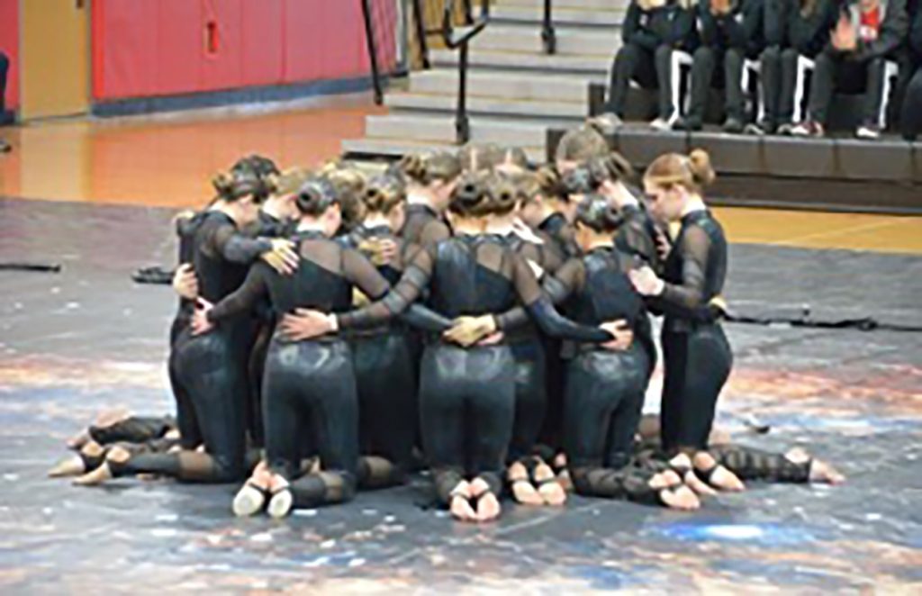 Dancers kneeling, hugging in a moment of silence