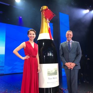 Two people pose with a giant promotional wine bottle