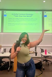 A person smiles while raising a hand, leading an activity