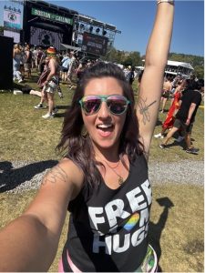 A smiling person raises a hand up high while holding camera for selfie