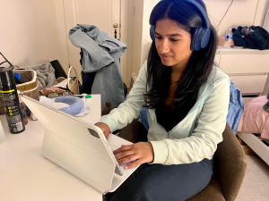 A woman works on her laptop with headphones