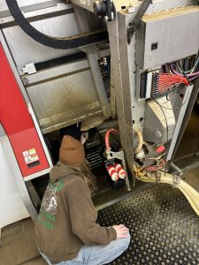 A woman reaches into farm machinery in an interior farm building