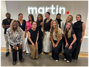 A group of people posing in front of a business logo