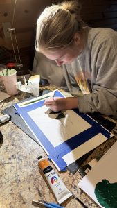 A person working at a table with art supplies