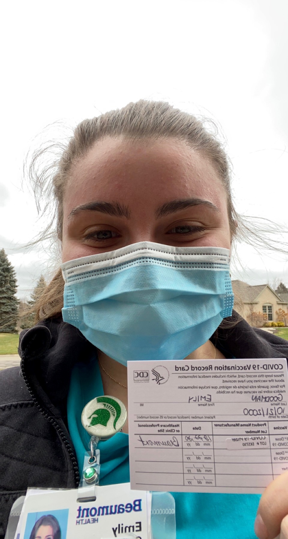 Masked woman holding inoculation card.