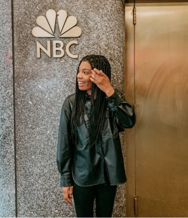 Woman leaning again wall with Peacock NBC logo