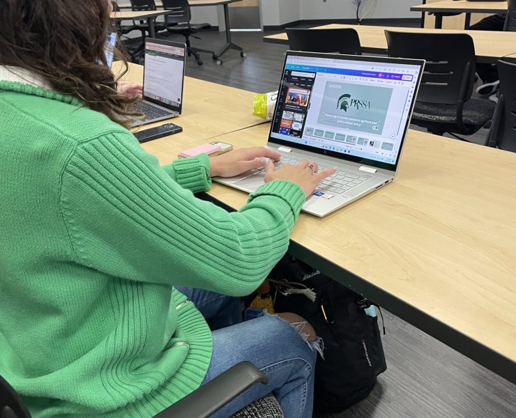 A person works on a laptop in a classroom.