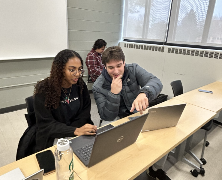 Two students working at a laptop in a classroom