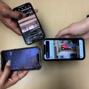 a closeup photograph of three hands holding smart phones; the screens all show social media platforms