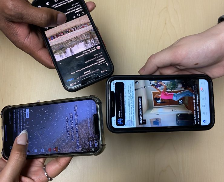 a closeup photograph of three hands holding smart phones; the screens all show social media platforms