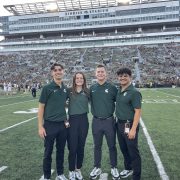 Four MSU students pose in front of large crowd at Kinnick Stadium