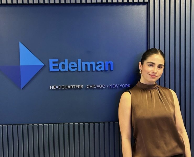 A person poses by a logo for a business.