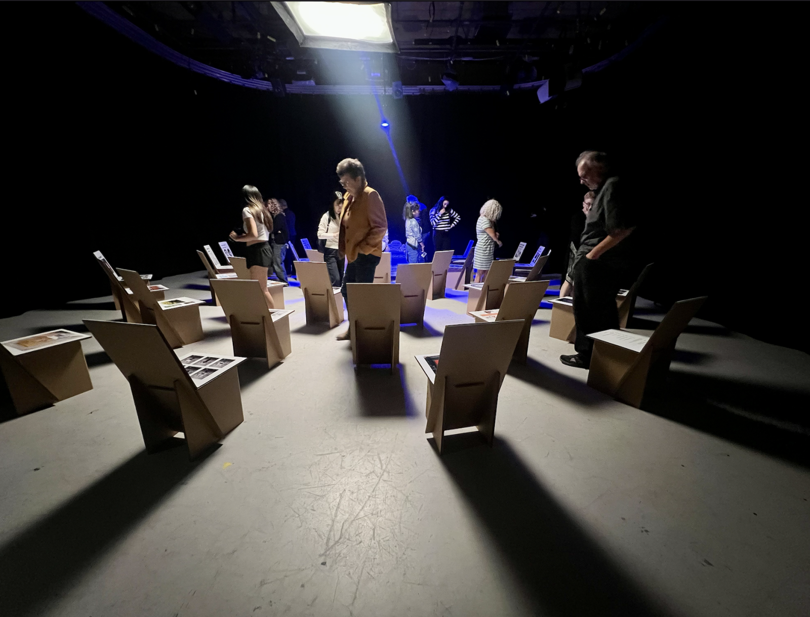 A group of people solemnly look at an art exhibit in a dimly lit room