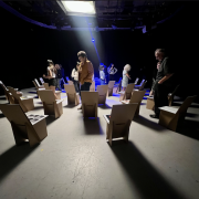 A group of people solemnly look at an art exhibit in a dimly lit room