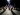 A group of people solemnly look at an art exhibit in a dimly lit room