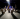 A group of people solemnly look at an art exhibit in a dimly lit room