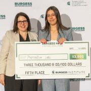 Two people smile while holding a presentation cheque.