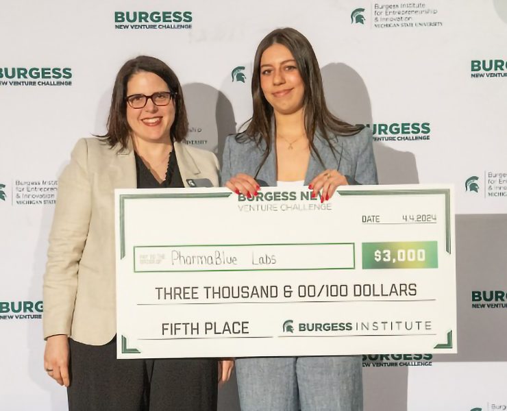Two people smile while holding a presentation cheque.