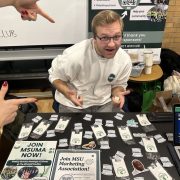 A student smiles at a table filled with swag.