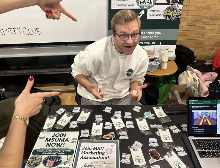 A student smiles at a table filled with swag.
