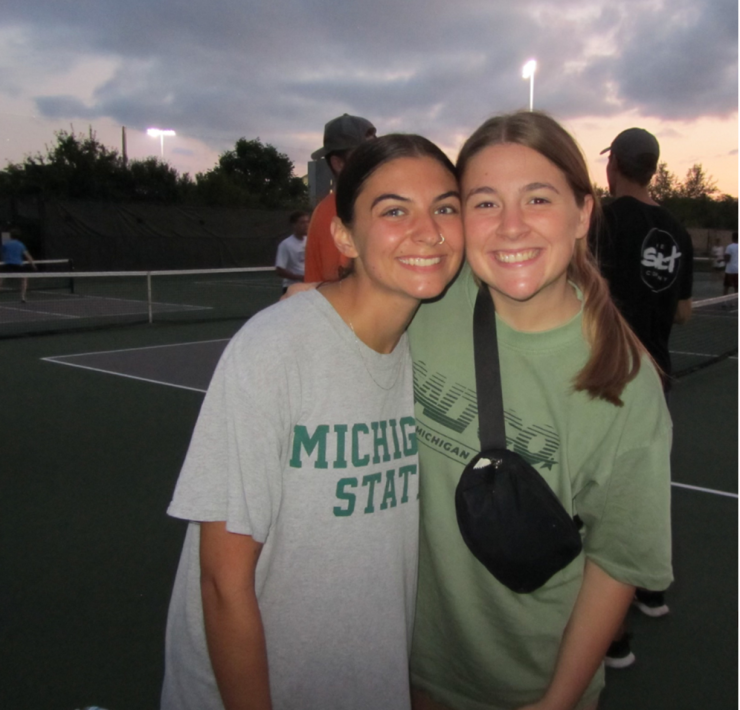 Two students smile while posing for a photograph outside