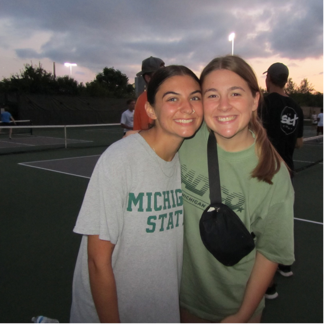 Two students smile while posing for a photograph outside