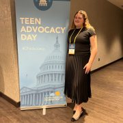 A person smiling in front of signage for a meeting.