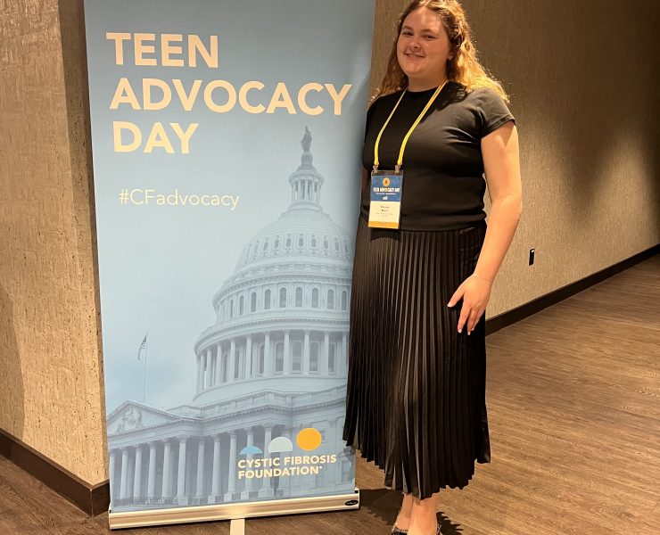 A person smiling in front of signage for a meeting.