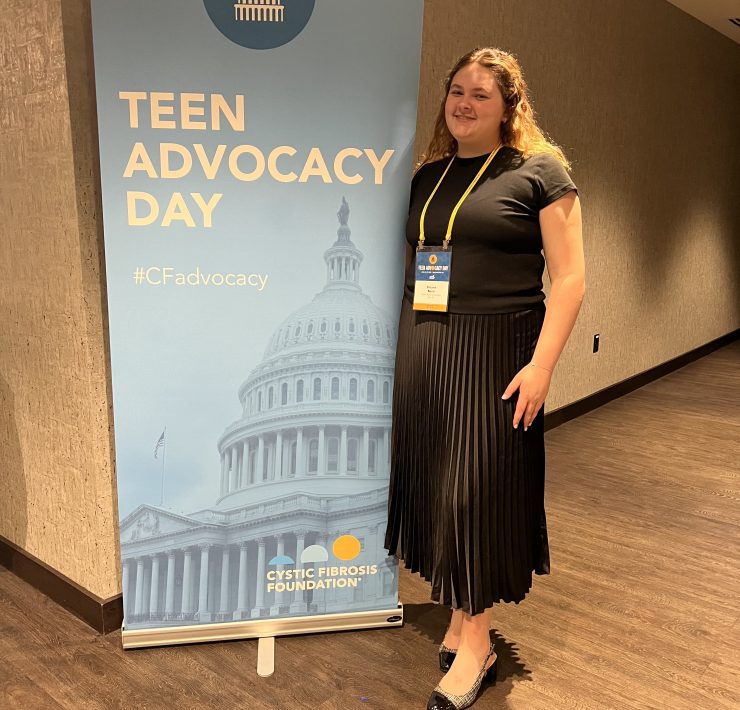 A person smiling in front of signage for a meeting.