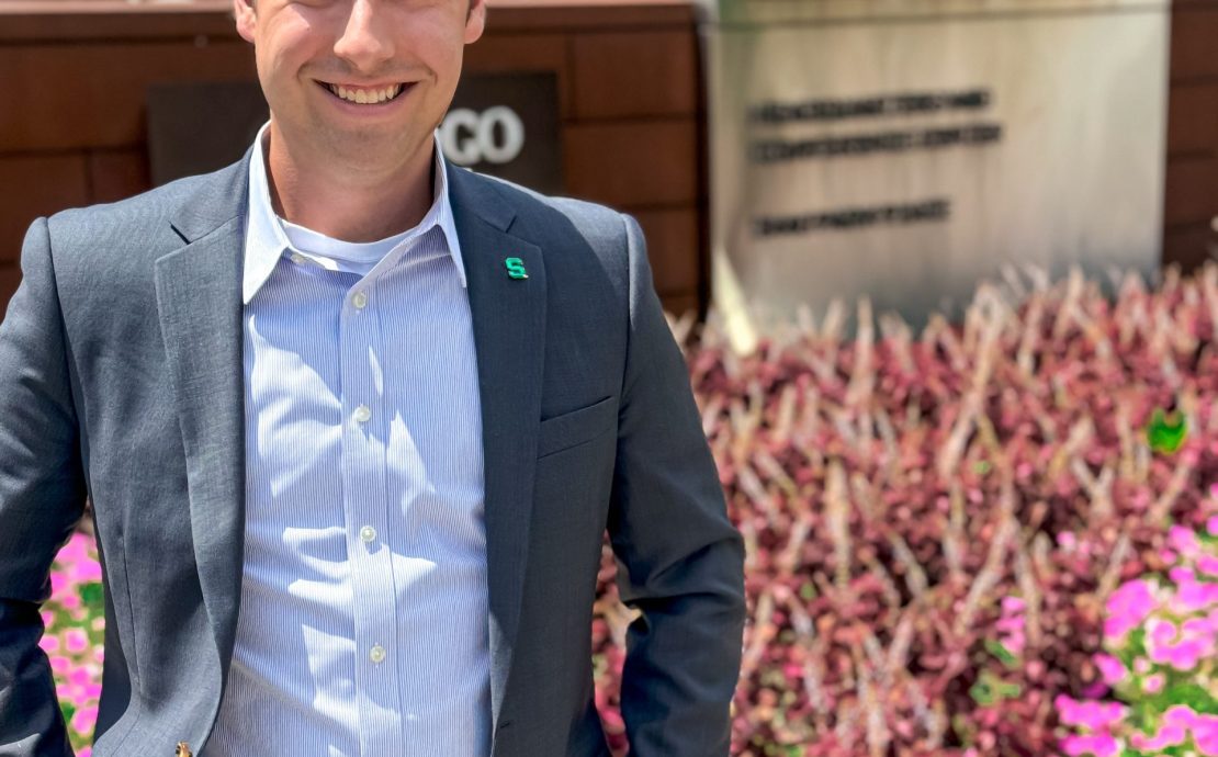 A person smiles by flowers