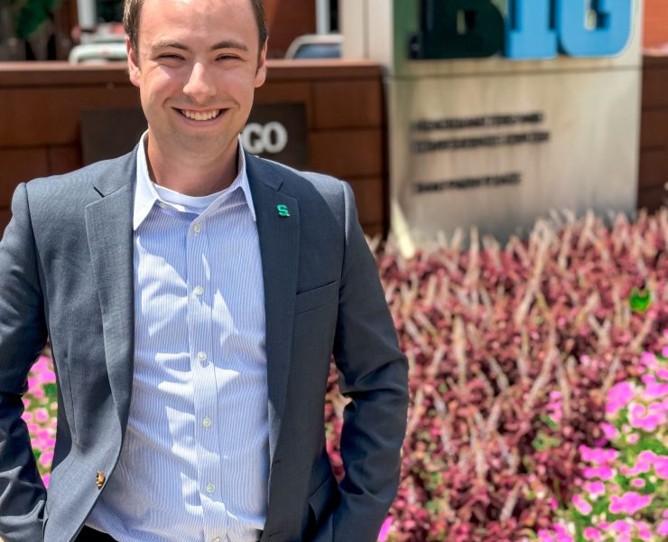 A person smiles by flowers