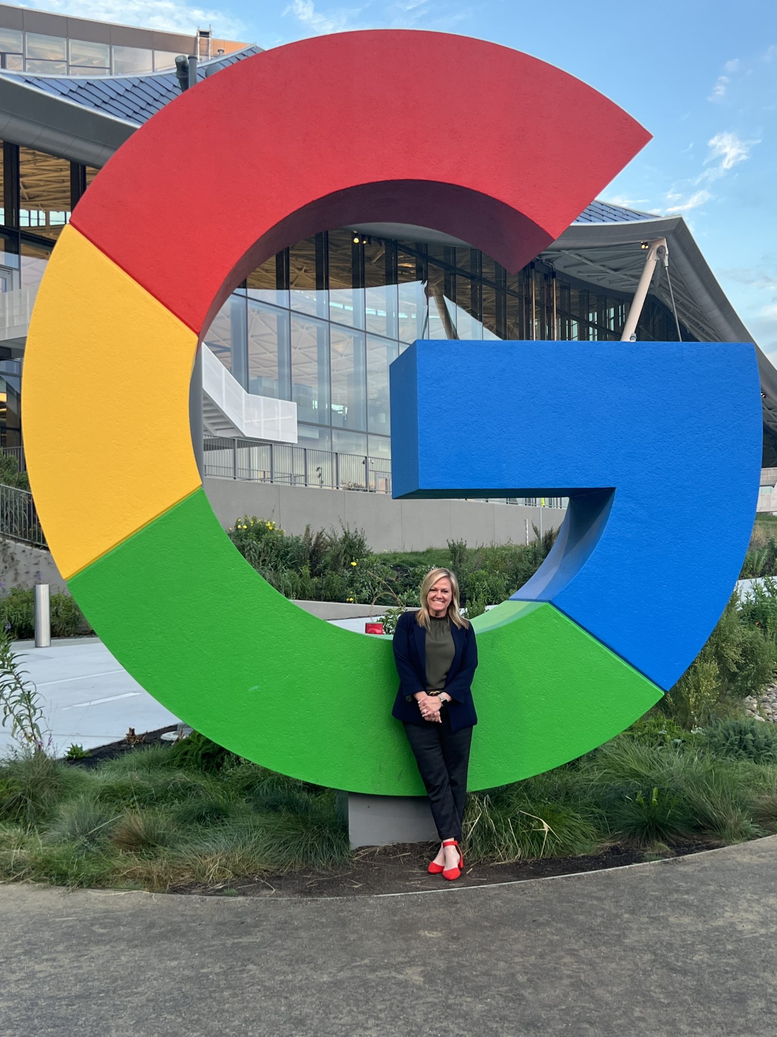 A person poses on a "G" from the google logo