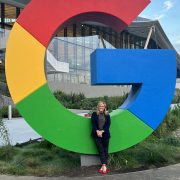 A person poses on a "G" from the google logo
