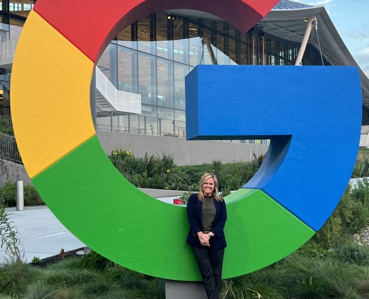 A person poses on a "G" from the google logo
