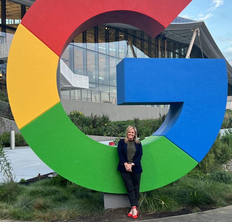 A person poses on a "G" from the google logo