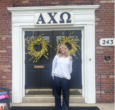 A student poses in front of a sorority house.