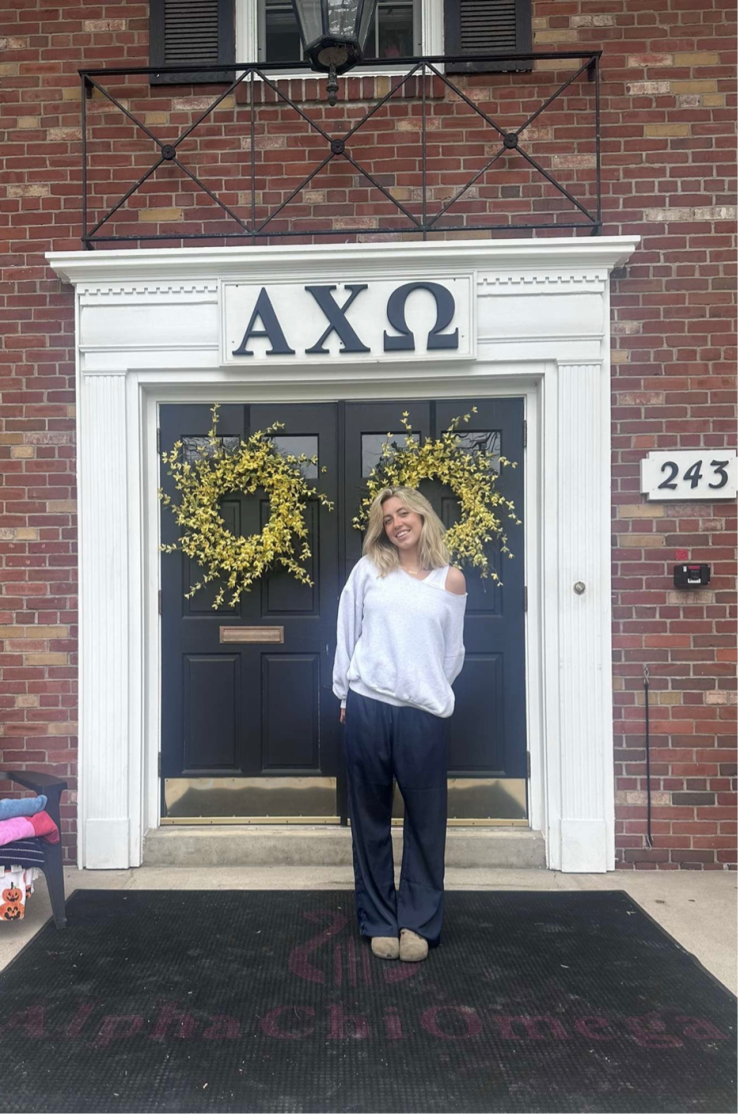A student poses in front of a sorority house.