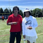 Two people stop for a smiling pose on a football field