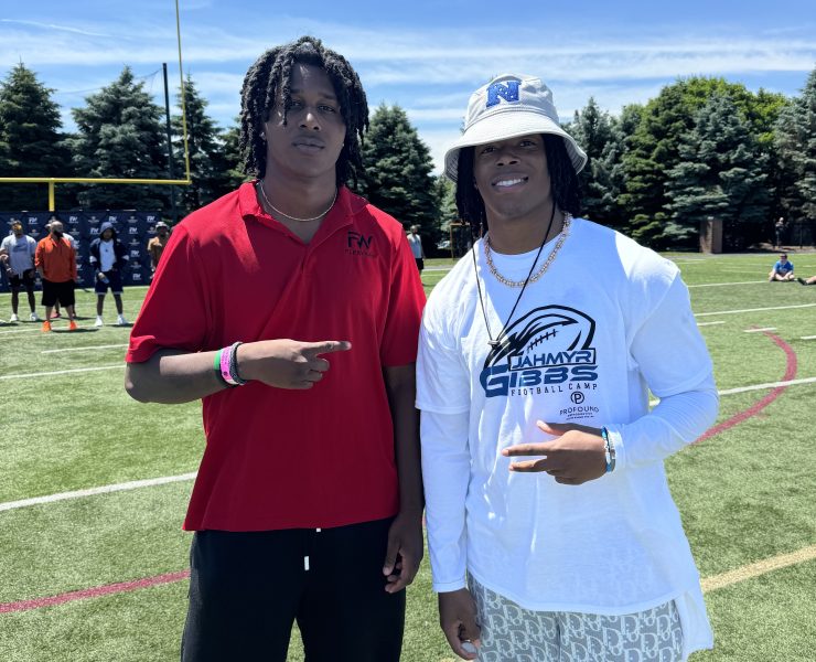 Two people stop for a smiling pose on a football field