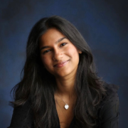 A woman smiles in front of a portrait background