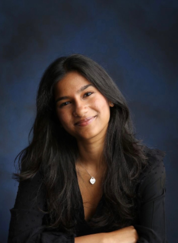 A woman smiles in front of a portrait background