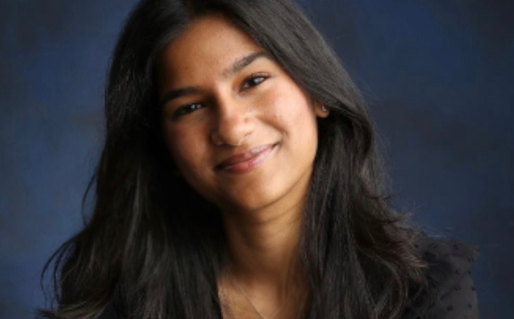 A woman smiles in front of a portrait background