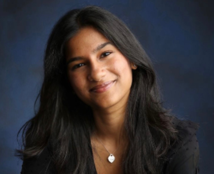 A woman smiles in front of a portrait background