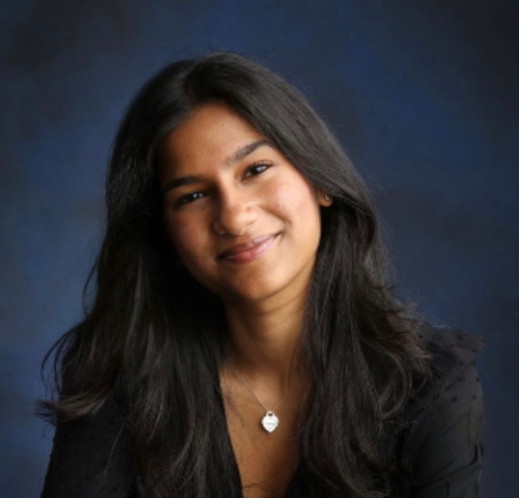 A woman smiles in front of a portrait background