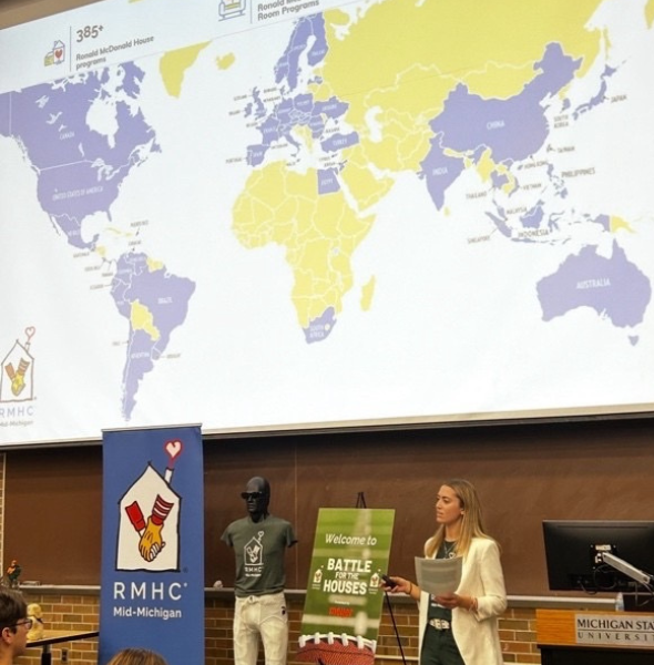 a woman presents with a map of the world behind her