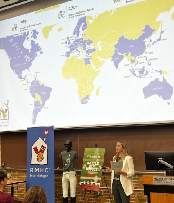 a woman presents with a map of the world behind her